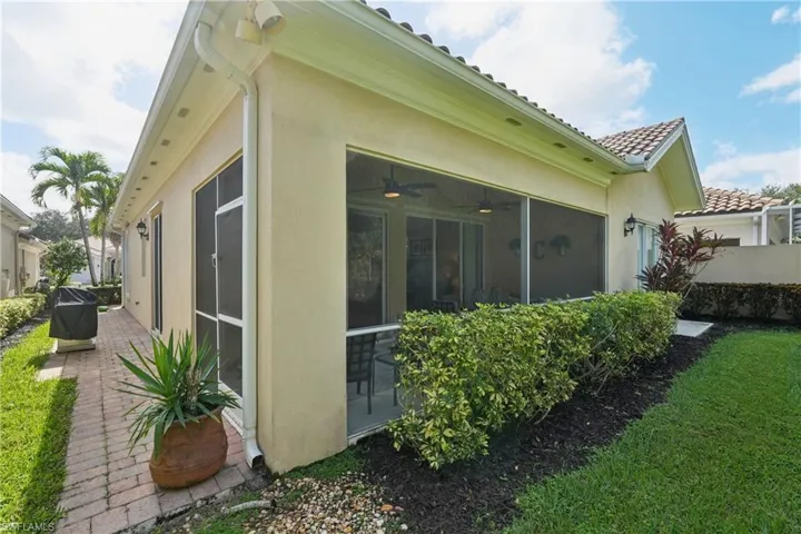 View of property exterior featuring a ceiling fan, stucco siding, a sunroom, and a tiled roof