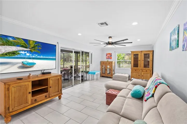 Spacious living area featuring light-toned tile flooring and crown molding