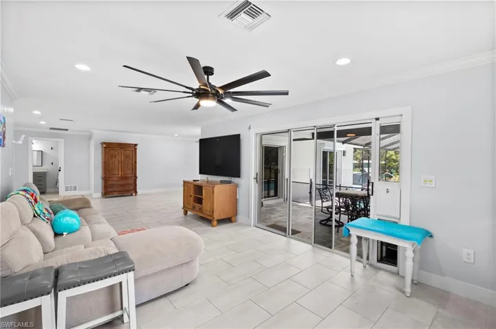 Spacious living area featuring light-toned tile flooring, recessed lighting, and crown molding