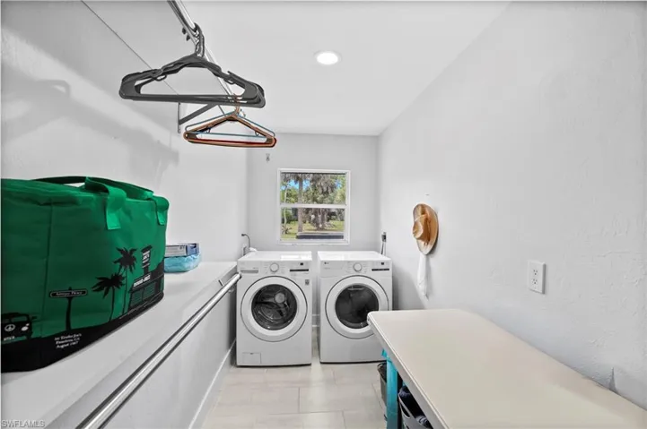 Dedicated laundry room featuring front-loading appliances, a built-in folding counter, and overhead hanging rod