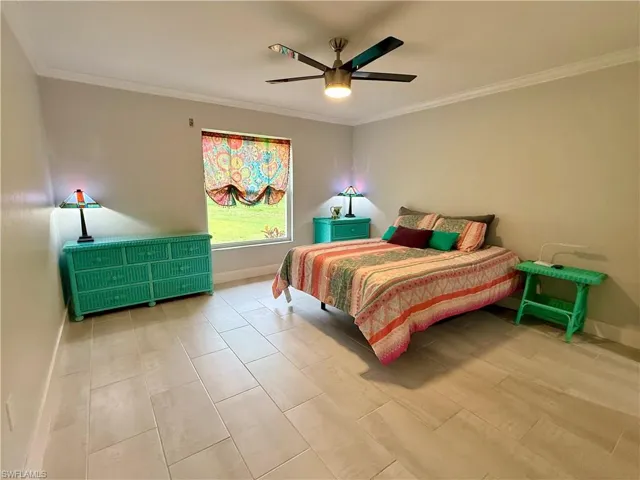 Spacious room featuring light-toned tile flooring, neutral wall paint, and white crown molding