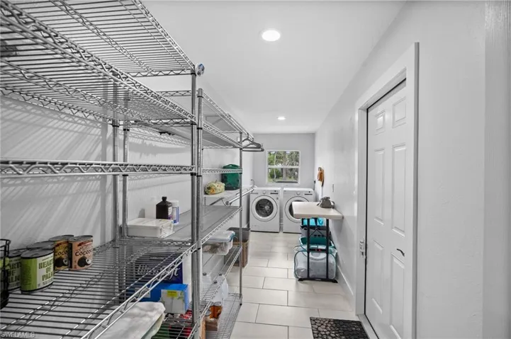 Laundry room featuring extensive chrome wire shelving, recessed lighting, light-toned floor tiling, and a window for natural illumination