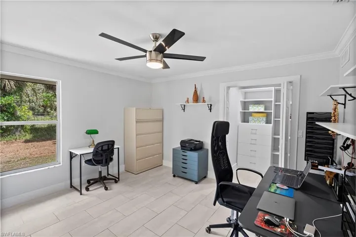 Spacious room featuring light-toned tile flooring and a ceiling fan with integrated lighting