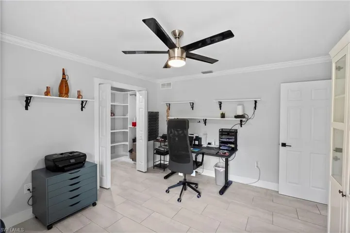 Neutral-toned room featuring light tile flooring and crown molding