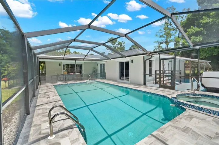 Screened outdoor living area featuring a rectangular pool with integrated spa
