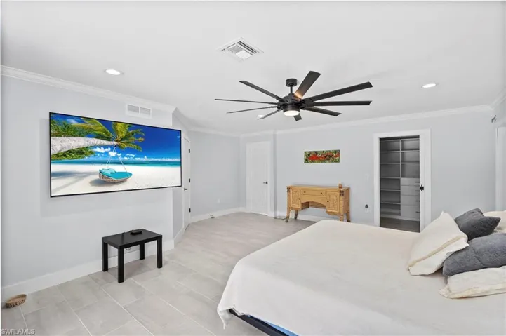 Spacious room featuring light gray walls, crown molding, recessed lighting, and tile flooring