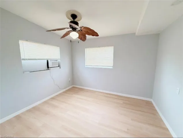 Empty room with baseboards, light wood-style floors, and a ceiling fan