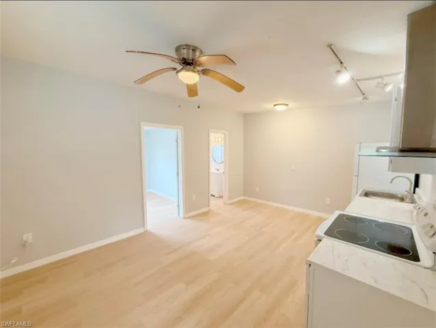 Laundry area featuring rail lighting, light wood-type flooring, baseboards, a sink, and a ceiling fan