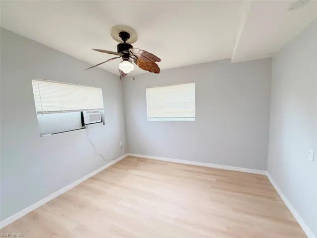 Unfurnished room with light wood finished floors, baseboards, and a ceiling fan