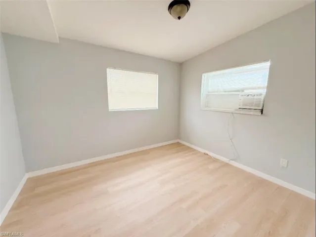 Unfurnished room with baseboards, light wood-style flooring, and a healthy amount of sunlight