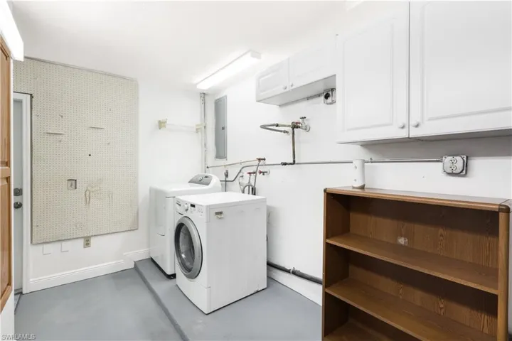 Laundry room featuring washing machine and dryer, cabinets, and electric panel