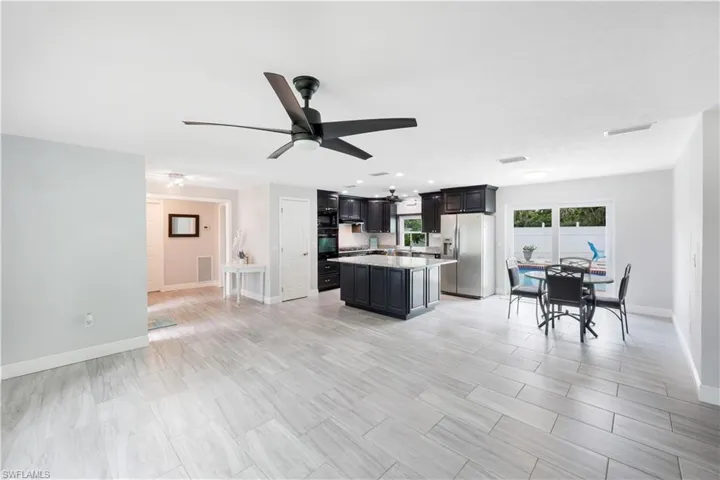 Kitchen with ceiling fan, oven, stainless steel fridge with ice dispenser, light tile patterned floors, and a kitchen island
