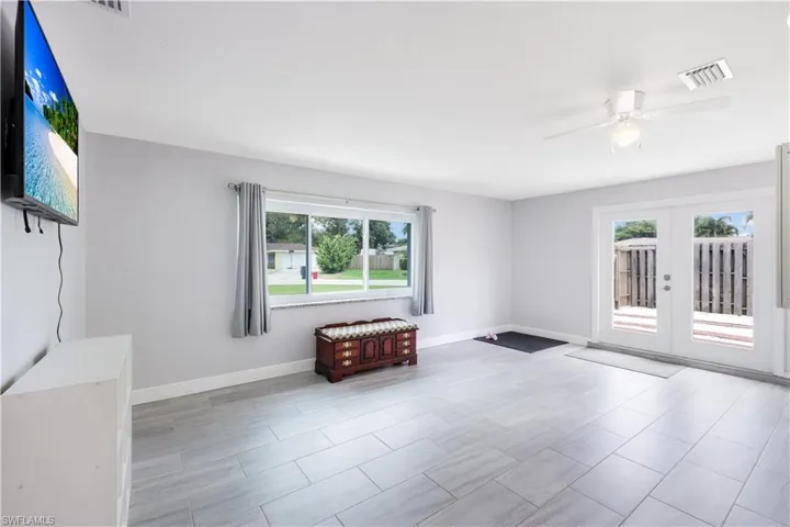 Tiled empty room with ceiling fan, french doors, and plenty of natural light