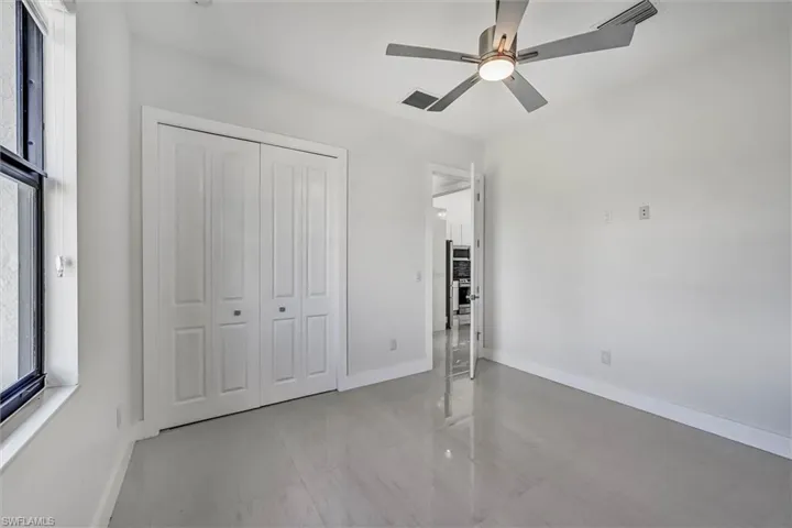 Room with neutral color palette, bifold closet doors, a contemporary ceiling fan, a window, and tile flooring