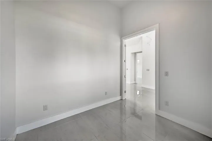 Spacious room featuring white walls and light-toned tile flooring
