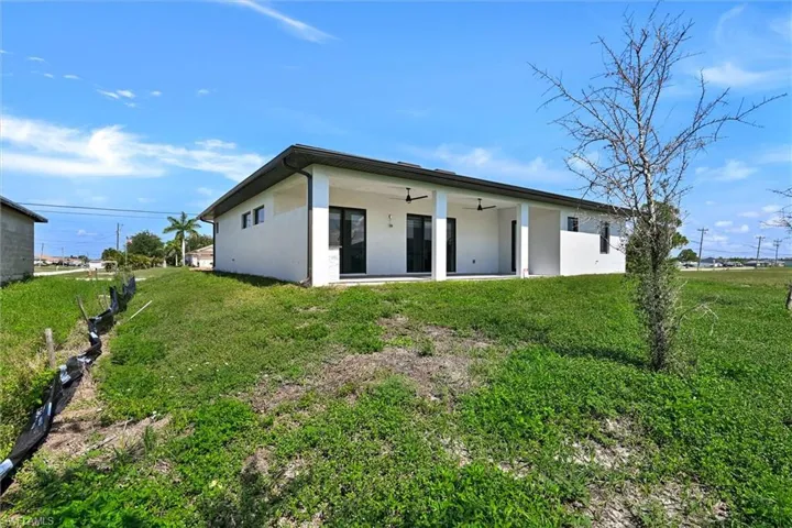 Rear exterior featuring a covered patio with integrated ceiling fans and black-framed sliding glass doors