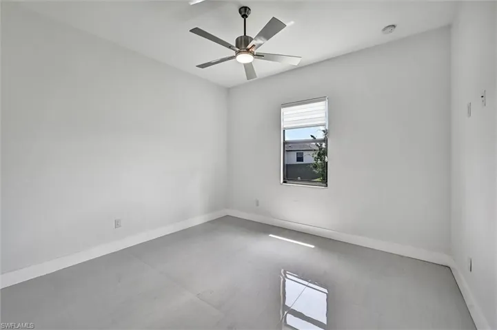 Spacious room with light gray tile flooring and white baseboards