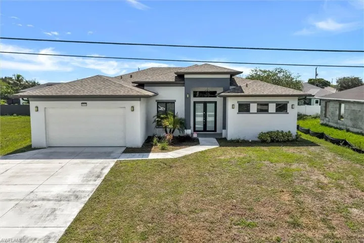 Contemporary stucco exterior featuring a grey accent facade, dark-framed double entry doors, a two-car garage, and a concrete driveway