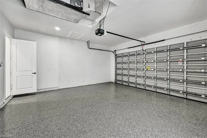Garage featuring a durable epoxy-coated floor, automatic garage door opener, and recessed ceiling lighting
