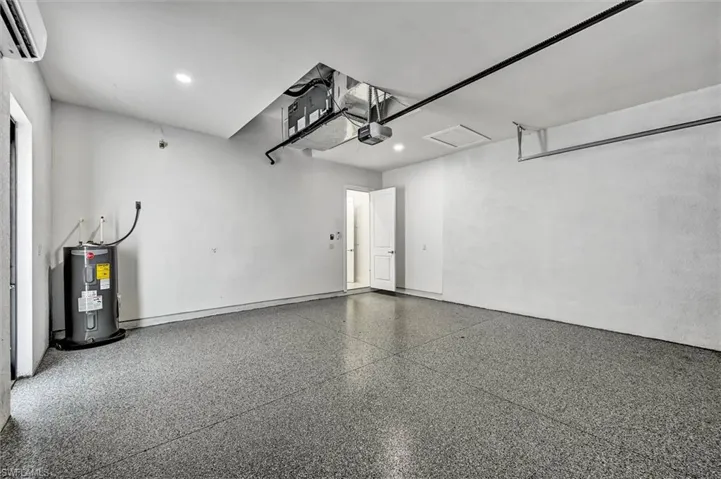 Spacious garage with an epoxy floor, recessed lighting, and a wall-mounted air conditioning unit
