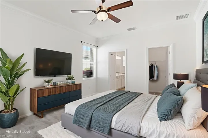 Bedroom featuring a walk in closet, carpet flooring, crown molding, a ceiling fan, and connected bathroom