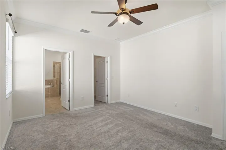 Unfurnished bedroom with crown molding, light carpet, connected bathroom, and ceiling fan
