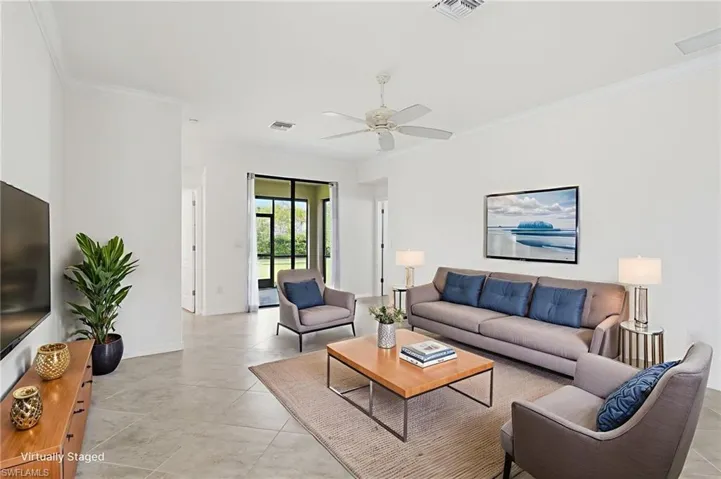 Living room featuring crown molding, a ceiling fan, and light tile patterned floors
