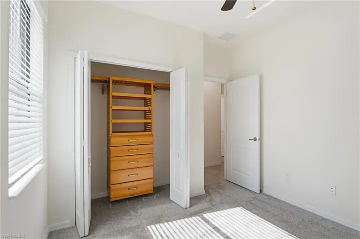 Bedroom with multiple windows, a closet, ceiling fan, and light colored carpet