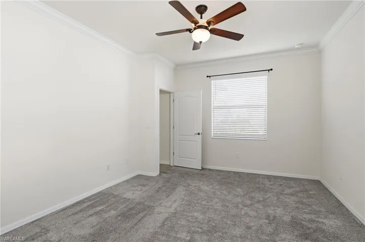 Unfurnished room featuring carpet floors, ornamental molding, and a ceiling fan