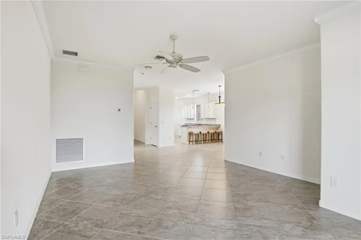 Spare room featuring ornamental molding, a ceiling fan, and light tile patterned flooring
