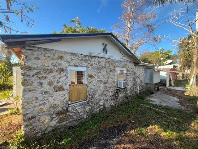View of side of property featuring stone siding, cooling unit, and stucco siding