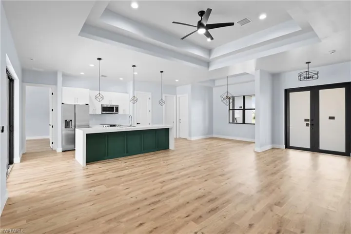 Kitchen featuring a center island with sink, open floor plan, pendant lighting, light wood finished floors, and stainless steel appliances