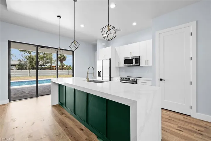 Kitchen with white cabinetry, a kitchen island with sink, recessed lighting, stainless steel appliances, and light stone countertops