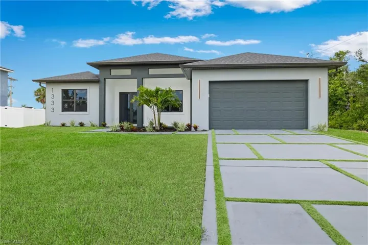 Prairie-style home with concrete driveway, stucco siding, a garage, and a shingled roof