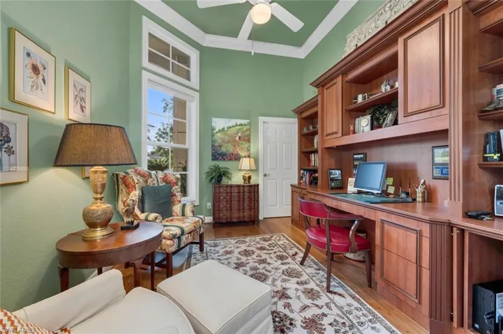 Office space with ceiling fan, dark hardwood / wood-style flooring, built in desk, and ornamental molding