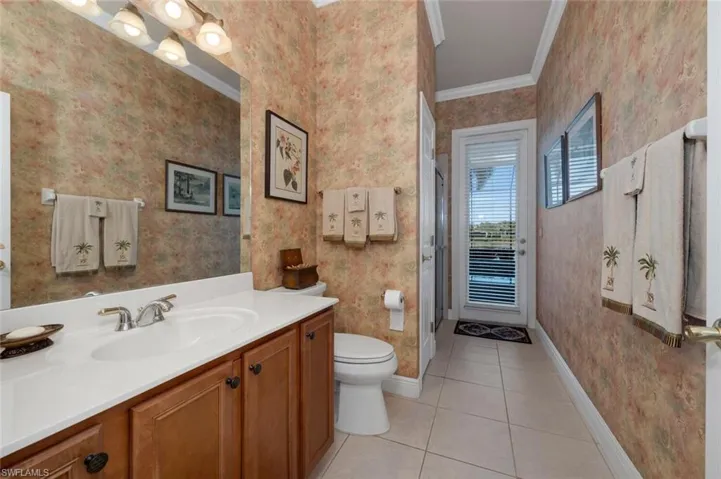 Bathroom featuring toilet, tile patterned flooring, vanity, and ornamental molding