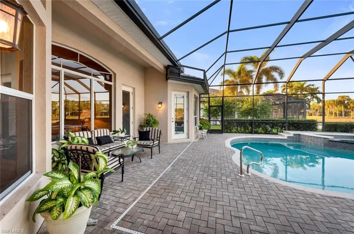 View of swimming pool featuring glass enclosure, a patio area, and an outdoor living space