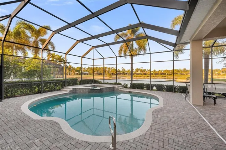 View of pool with an in ground hot tub, a patio, a water view, and a lanai