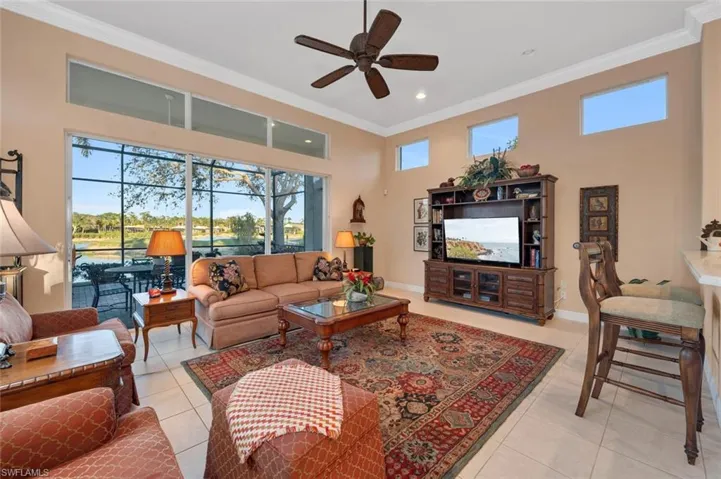 Living room with ceiling fan, light tile patterned flooring, and ornamental molding