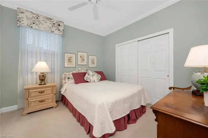 Bedroom with ceiling fan, crown molding, light carpet, and a closet