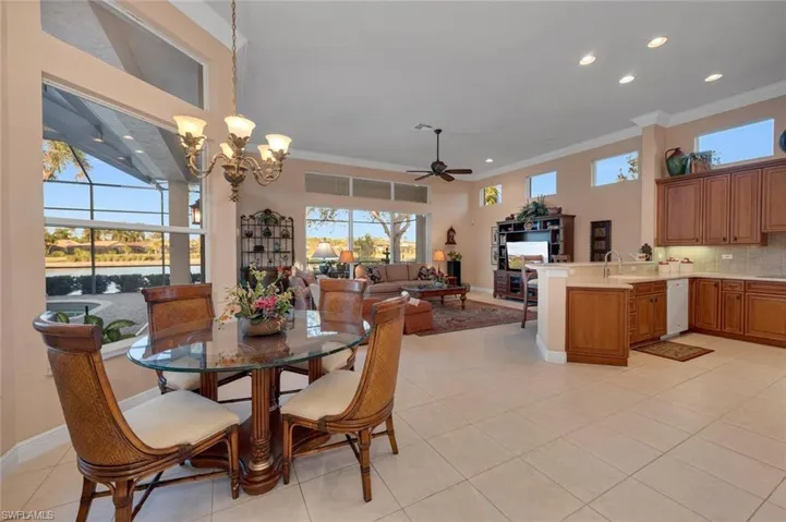 Dining area with light tile patterned floors, ceiling fan with notable chandelier, and ornamental molding