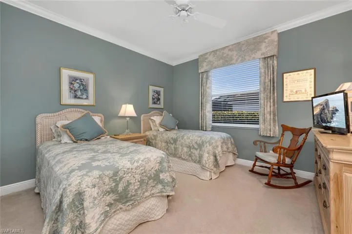 Carpeted bedroom with ceiling fan and ornamental molding