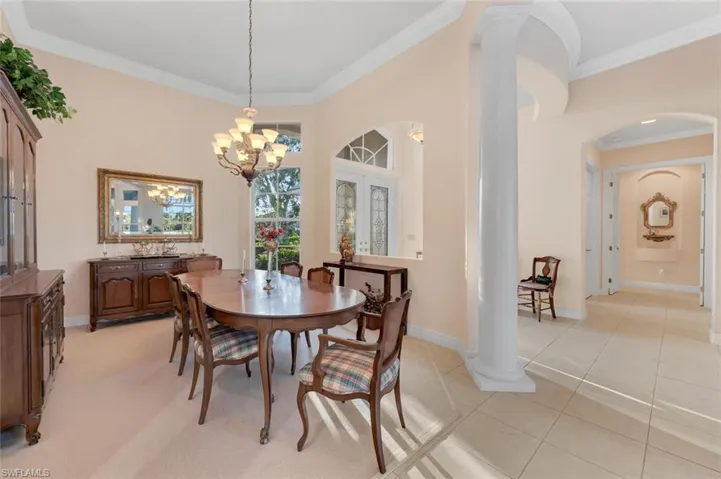 Dining space featuring decorative columns, light tile patterned floors, a notable chandelier, and ornamental molding