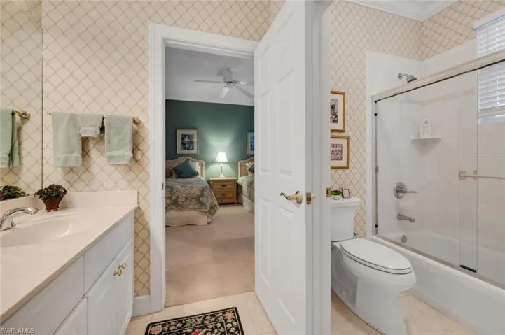 Full bathroom with ceiling fan, tile patterned flooring, crown molding, shower / bath combination with glass door, and vanity