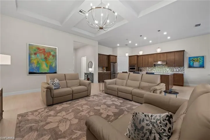 Living room with beamed ceiling, a chandelier, and coffered ceiling