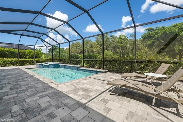 View of swimming pool with glass enclosure, a patio area, and an in ground hot tub