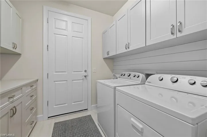 Washroom featuring cabinets, shiplap walls, bench, independent washer and dryer, and light tile patterned flooring