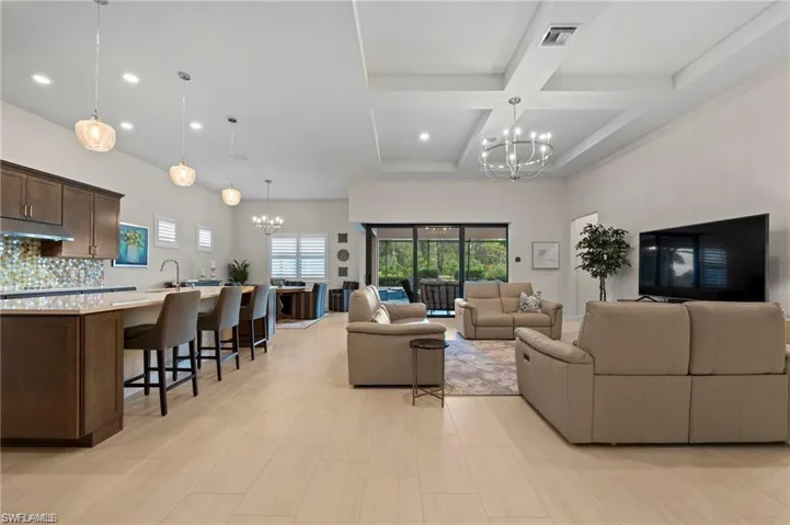 Living room with beamed ceiling, sink, coffered ceiling, and an inviting chandelier