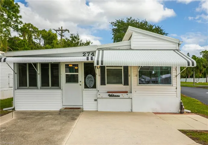 Exterior featuring horizontal siding, a covered concrete driveway, metal awnings, and multi-pane windows