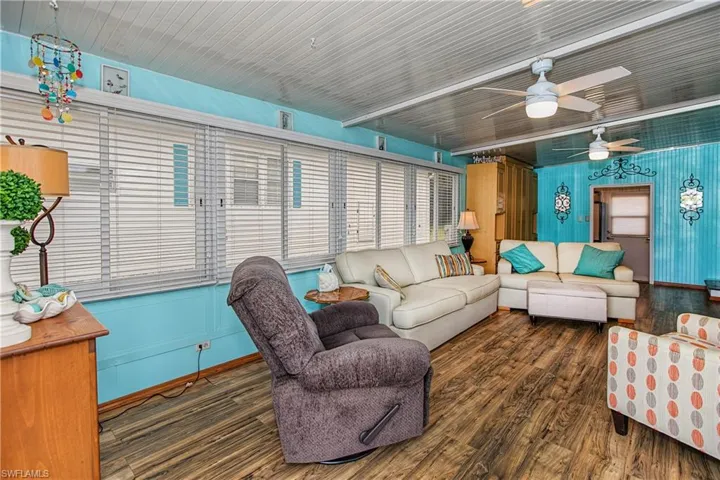 Sunroom featuring wood-finish flooring, paneled walls, ceiling-mounted fans, and extensive horizontal window blinds